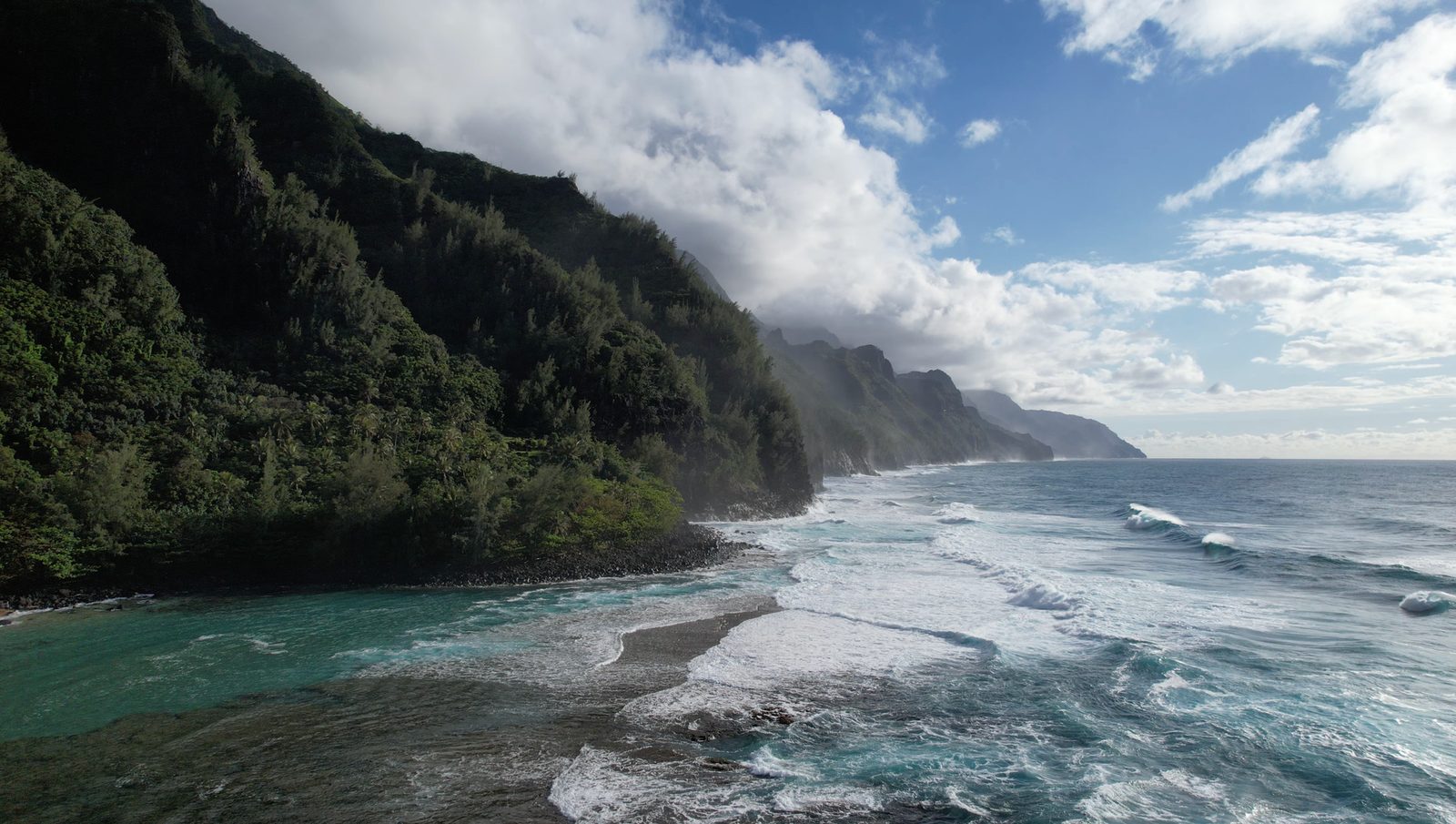 Aerial view of the Nā Pali coastline, ridged cliffs meeting the Pacific